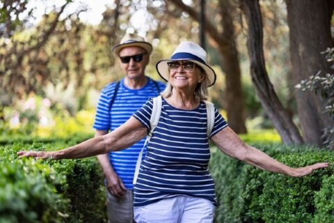 A senior couple walking through a garden during the summer.