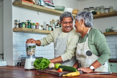 A senior couple preparing a healthy smoothie in the kitchen at home.