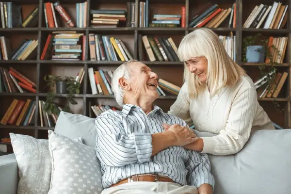 A senior couple spending time together and smiling in the living room.