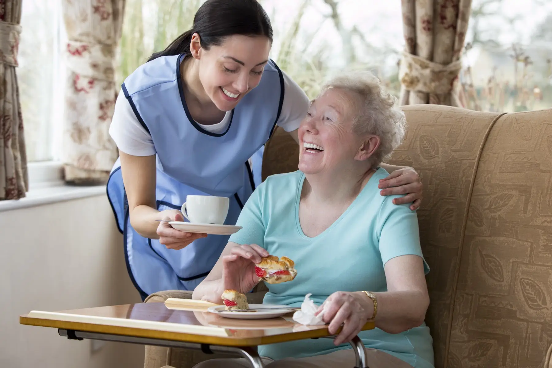 Senior Woman Enjoying Afternoon Tea Happy old woman enjoying a Scone and cup of tea with carer
