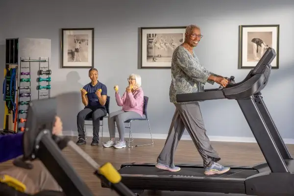 A senior woman performing light strength exercises at a gym to support mobility and manage arthritis symptoms.