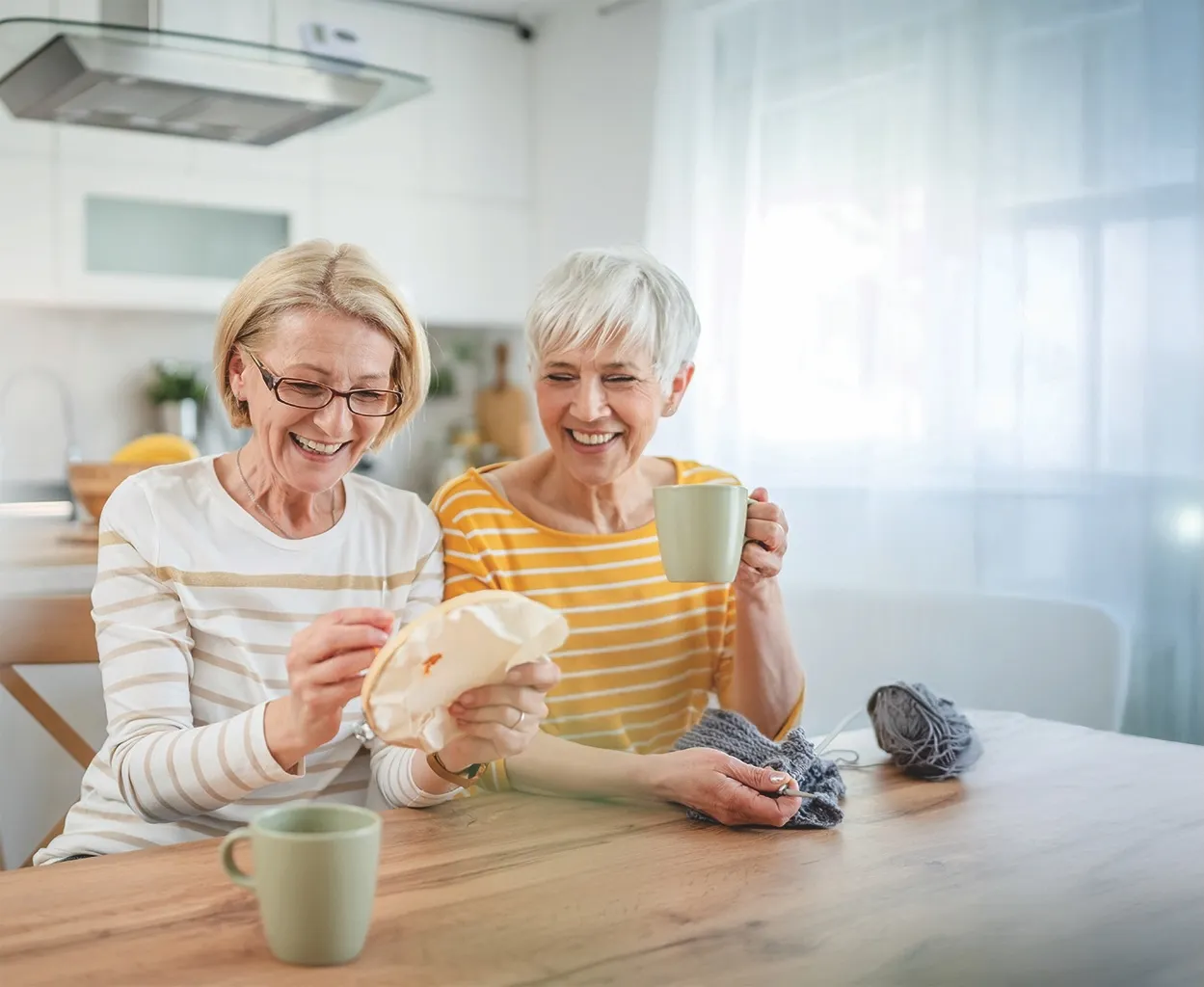 complete-guide-to-senior-housing-women-having-coffee Senior friends having coffee and sewing together.