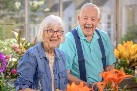 A happy senior couple tends to their garden.