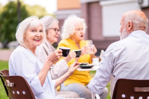 A senior woman enjoys coffee with her community friends.