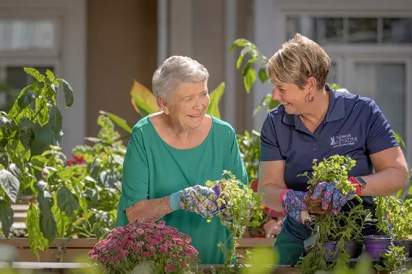 A senior and a Senior Lifestyle team member work on a garden.