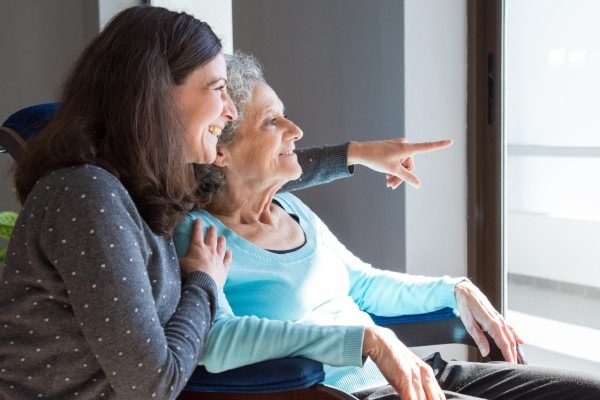 A woman and her senior mom look out a window.